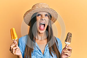 Young hispanic woman wearing summer style holding ice cream angry and mad screaming frustrated and furious, shouting with anger