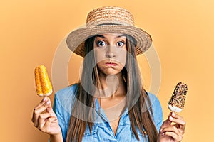 Young hispanic woman wearing summer style holding ice cream puffing cheeks with funny face