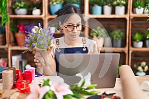 Young hispanic woman working at florist shop doing video call showing middle finger, impolite and rude fuck off expression