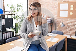 Young hispanic woman working at the office wearing glasses doing happy thumbs up gesture with hand