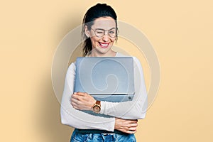 Young hispanic woman working using computer laptop winking looking at the camera with sexy expression, cheerful and happy face