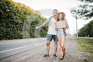 Young hitchhiking couple with empty cardboard