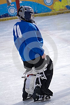 Young hockey goalie poses without her face-mask on a black background.