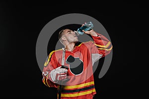 young hockey player drinking water from sports bottle