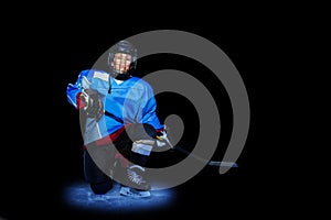 Young hockey player spotlighted on dark background