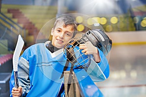 Young hockey player standing next to rink boards