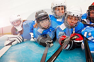 Young hockey players with sticks laying on ice