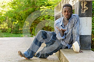 Young homeless African man begging for food on the bridge