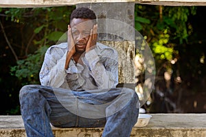 Young homeless African man looking depressed on the bridge
