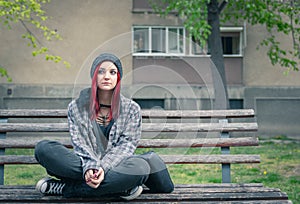 Young homeless girl sitting on the street on the bench