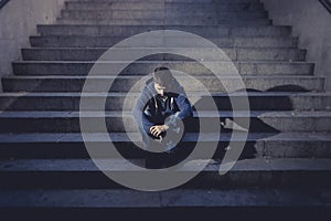 Young homeless man lost in depression sitting on ground street concrete stairs