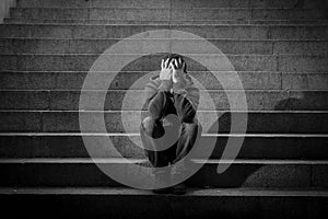 Young homeless man lost in depression sitting on ground street concrete stairs