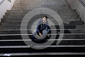 Young homeless man lost in depression sitting on ground street concrete stairs