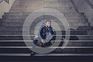 Young homeless man lost job in crisis suffering depression sitting on ground street concrete stairs