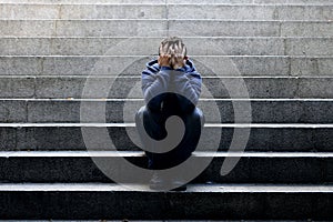 Young homeless man lost job sitting in depression on ground street concrete stairs