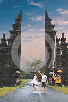 Young honeymoon couple on a big balinese gates background. Bali island, Indonesia.
