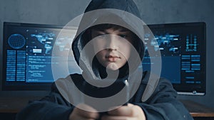 Young hooded hacker kid using a smartphone device to hijack. Genius boy wonder hacks system at cyberspace.