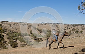 Young horse instructor or cattleman riding the animal in cowboy hat and rider boots