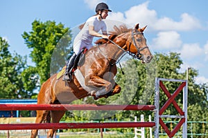 Young horse rider girl jumping on show jumping