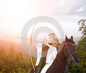 Young horseback girl shooting arrow from bow