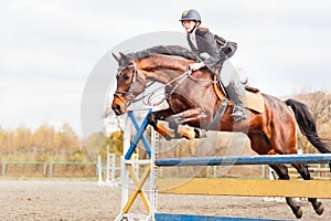 Young horseback sportsgirl jumping on show jumping