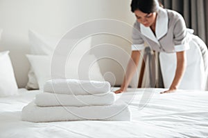 Young hotel maid setting up pillow on bed photo