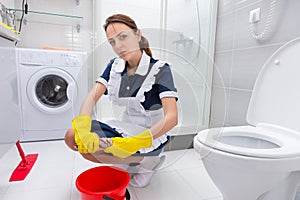 Young housekeeper or maid cleaning the floor