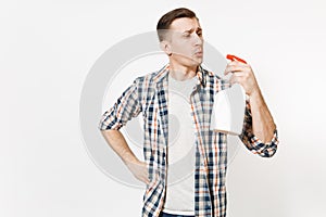 Young housekeeper man in checkered shirt blowing on white blank empty cleaning spray bottle with cleaner liquid isolated