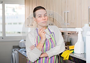 Young housewife in gloves is bushed after cleaning kitchen with detergent