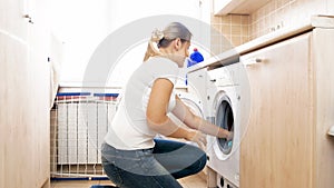 Young housewife loading clothes in washing machine