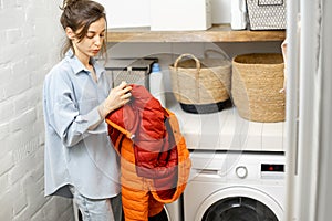 Young housewife looks on a down jacket before washing