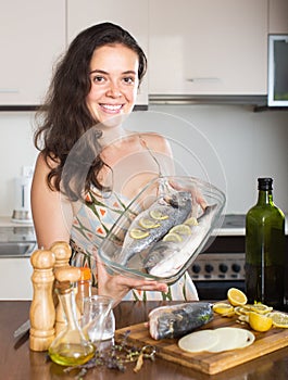 Young housewife prepare fish dorado in frying pan