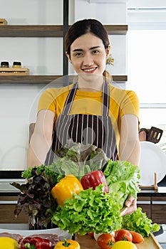 Young housewife smiled and offered a basket full of various kinds of vegetables on the front