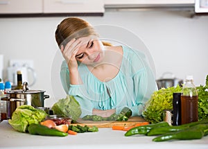 Young housewife tired of cooking vegetables in domestic kitchen