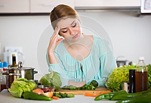 Young housewife tired of cooking vegetables in domestic kitchen