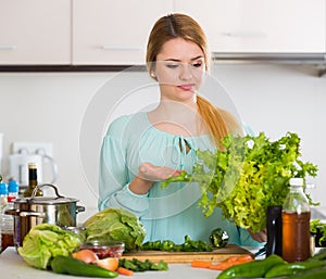 Young housewife tired of cooking vegetables in domestic kitchen