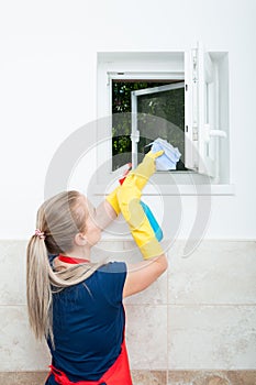Young housewife wiping the window