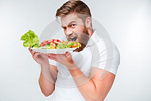 Young hungry bearded man eating salad