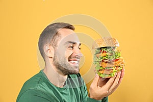 Young hungry man eating huge burger