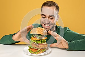 Young hungry man eating huge burger