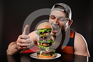 Young hungry man eating huge burger
