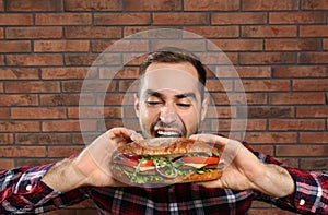 Young hungry man eating tasty sandwich