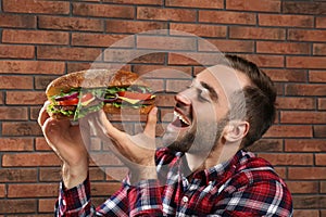Young hungry man eating tasty sandwich
