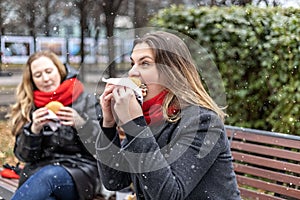 Young hungry woman eats Burger and takes lunch break outdoors in Park.Fast food. Takeaway food concept