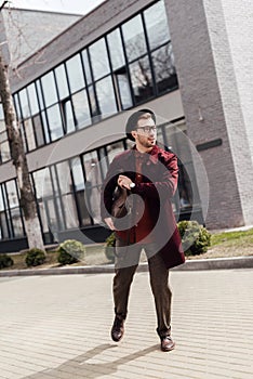 young hurry man in trendy clothes with bag running