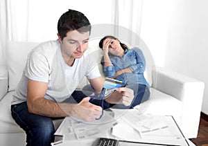 Young husband cutting credit card with scissors woman depressed