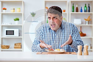 The young husband eating tasteless food at home for lunch