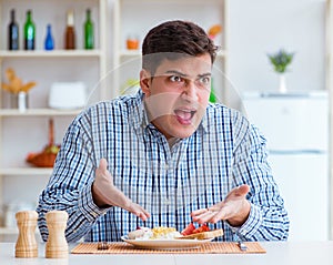 Young husband eating tasteless food at home for lunch