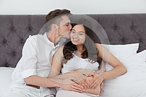 Young husband and his pregnant wife showing heart