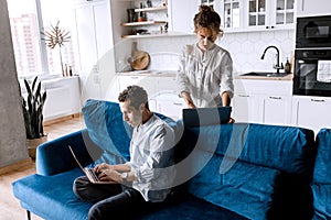Young husband and wife using laptops computers manage finances, bills, tax together sit at home sofa, planning budget